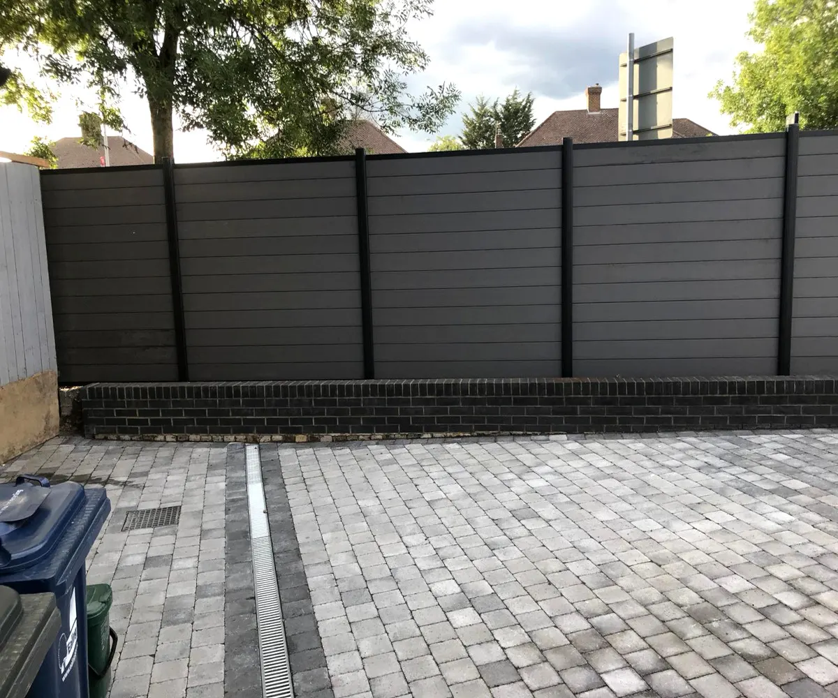 Grey composite fencing beside a block paved driveway