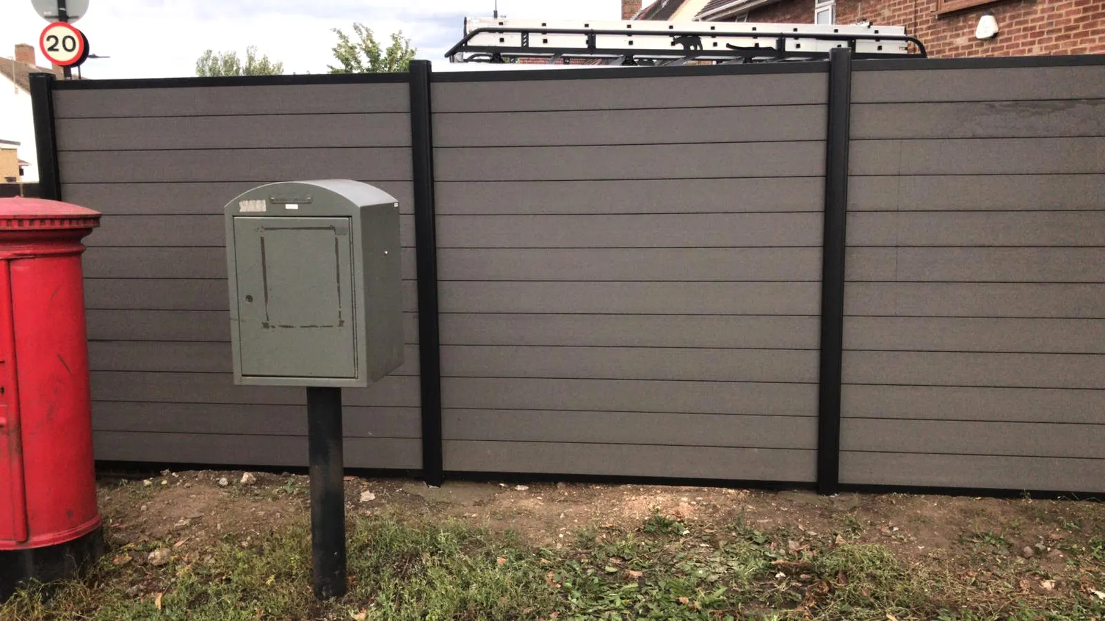 Grey composite fencing on a London street next to a red Royal Mail pillar box