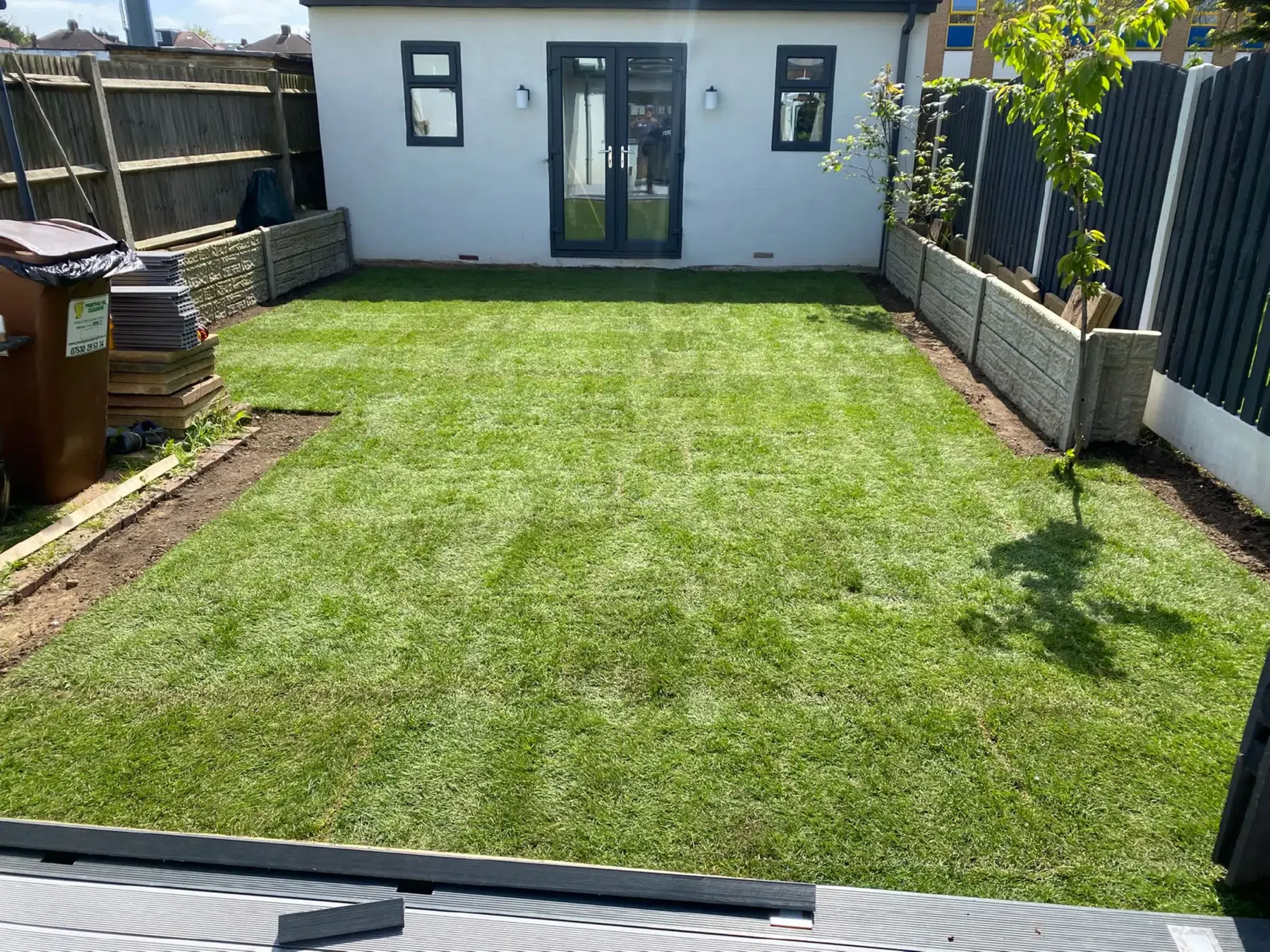 A new lawn in front of a garden room with a black fence